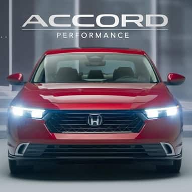 2026 Honda Accord Touring Hybird front view in Radiant Red Metallic with LED lights on.
